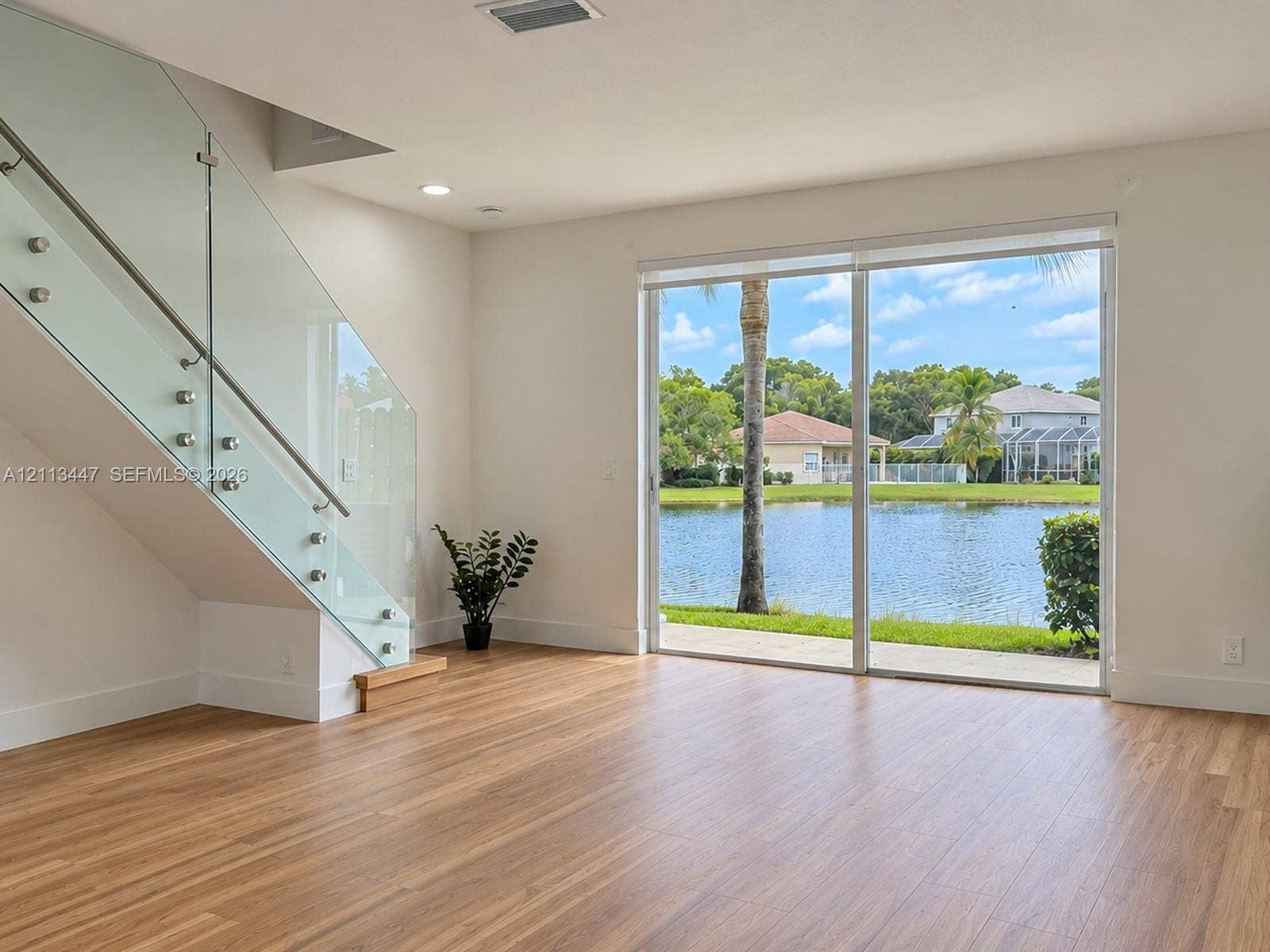3818 San Simeon Circle, #3818, Weston, Weston, FL 33331 Staircase featuring a glass railing with stainless steel standoffs, luxury laminate flooring, and expansive sliding glass doors...