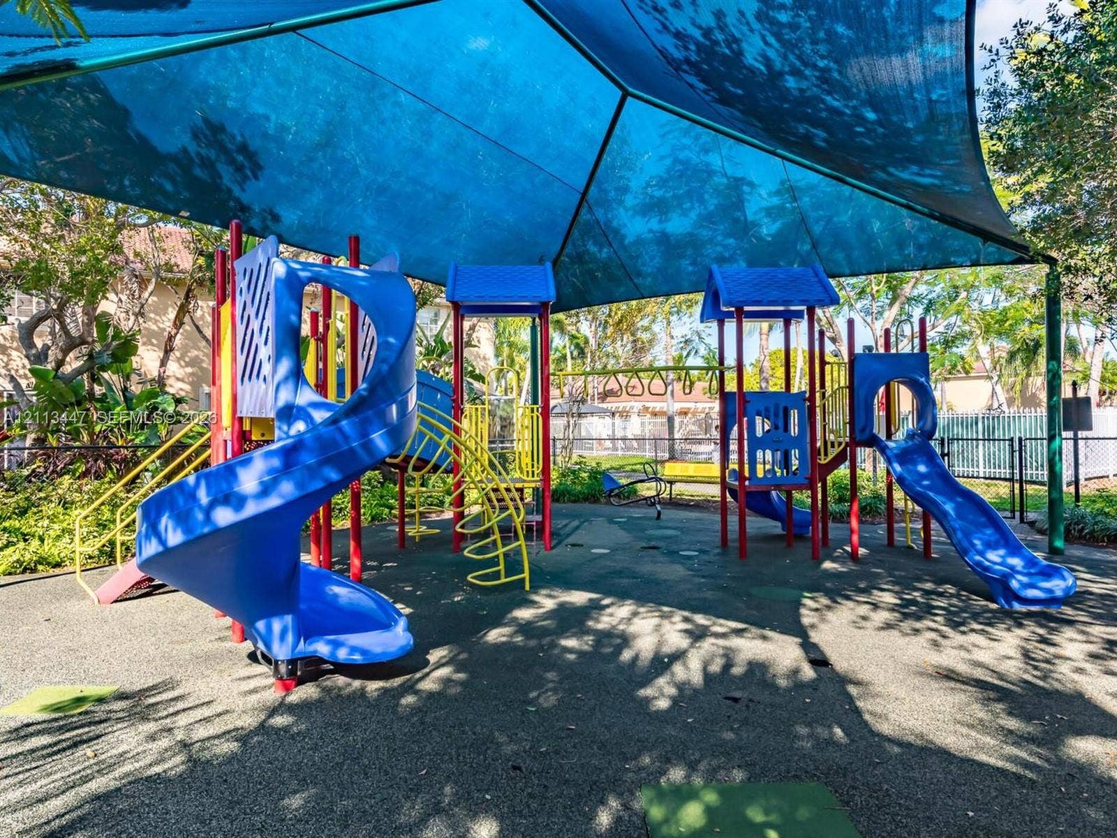 3818 San Simeon Circle, #3818, Weston, Weston, FL 33331 Playground area featuring a multi-level structure with spiral and straight slides, overhead ladder, protective shade canopy, and poured-in-place rubber surfacing