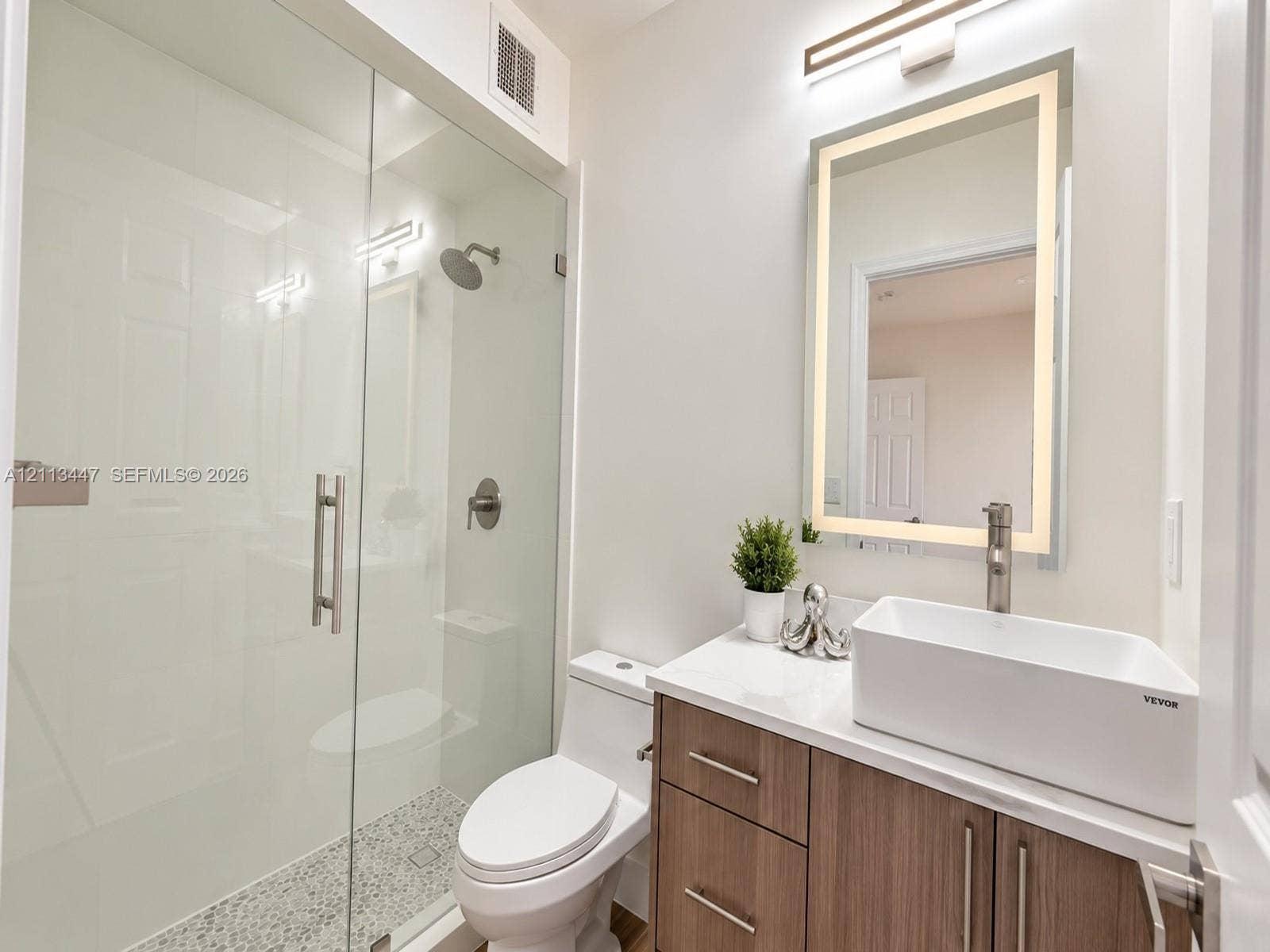 3818 San Simeon Circle, #3818, Weston, Weston, FL 33331 Bathroom featuring a glass-enclosed shower with pebble-tile flooring, a wood-finish vanity with a vessel sink, and an integrated LED-lighted mirror