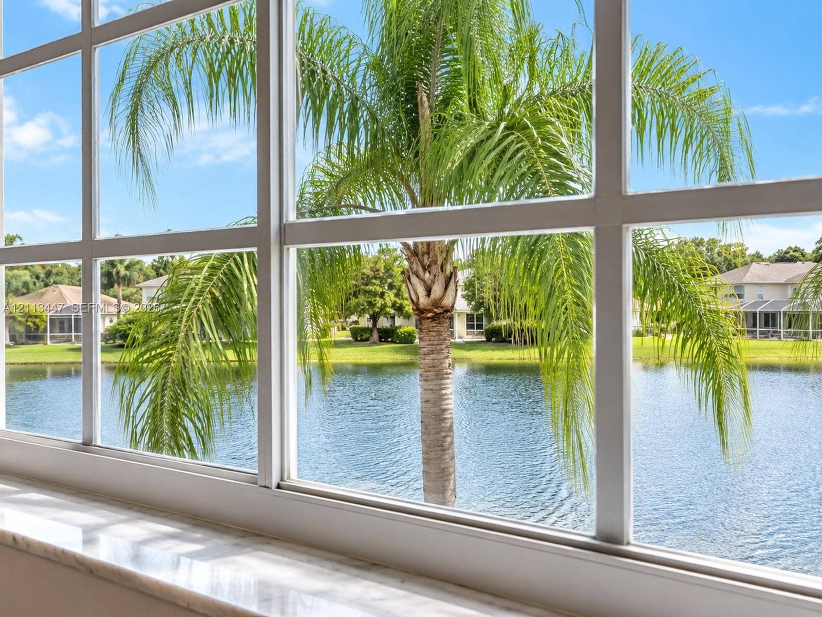 3818 San Simeon Circle, #3818, Weston, Weston, FL 33331 Grid-pattern multi-lite window featuring a natural stone sill, framing a waterfront landscape with palm trees