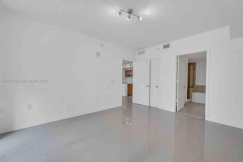 Neutral-toned polished tile flooring, multi-directional track lighting, and solid core interior doors