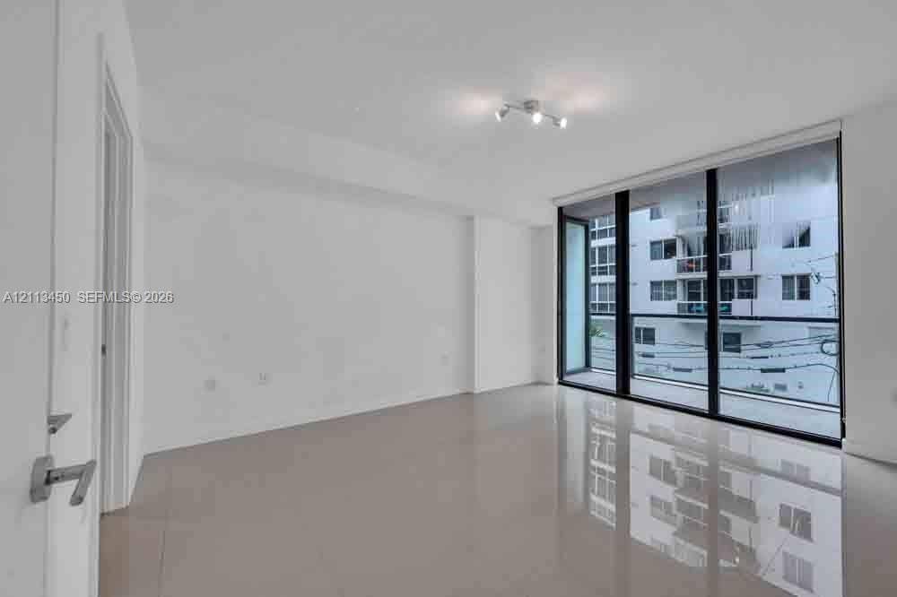 Floor-to-ceiling glass windows, polished tile flooring, and multi-light directional ceiling fixture