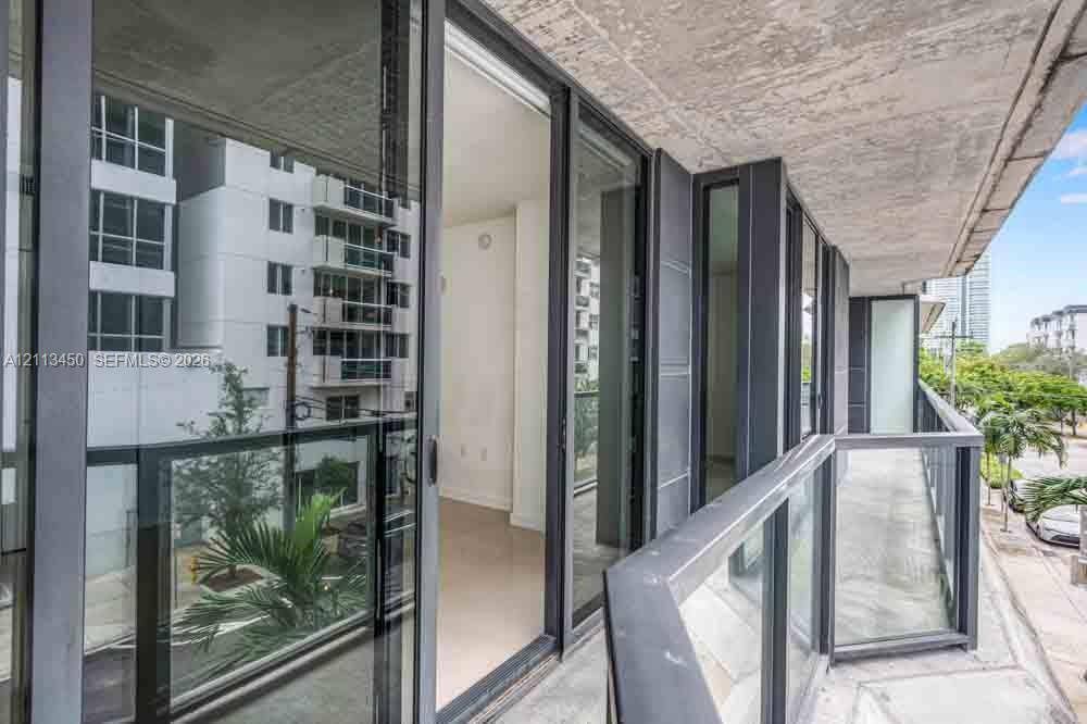 Private balcony featuring concrete flooring, a glass panel railing with a dark metal frame, and sliding glass door access