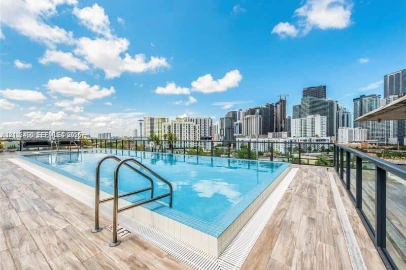 Rooftop swimming pool with tile surfacing, metal railings, and wood-finish flooring