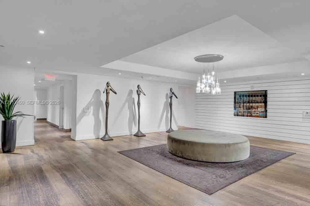 Open-concept interior featuring wood-finish flooring, a tiered multi-light chandelier, recessed lighting, and horizontal shiplap wall detailing