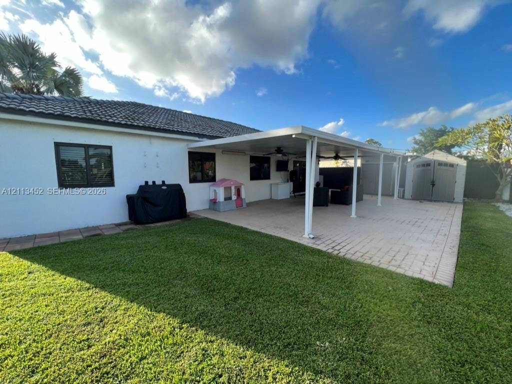 5083 SW 160th Avenue, Miami, Miami, FL 33185 Backyard featuring a paved patio, a covered lanai with ceiling fans, and a detached storage shed