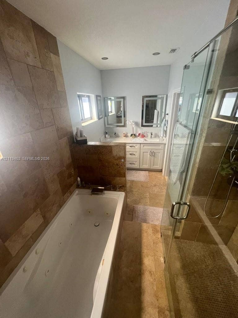 5083 SW 160th Avenue, Miami, Miami, FL 33185 Jetted soaking tub with tile surround, walk-in glass-enclosed shower, dual-sink vanity with cabinetry, and stone-finish flooring
