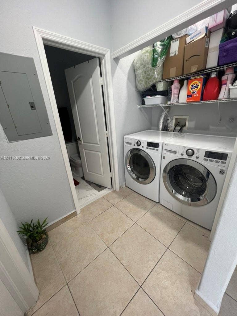 5083 SW 160th Avenue, Miami, Miami, FL 33185 Laundry area featuring large-format tile flooring, built-in wire shelving, and an integrated electrical service panel