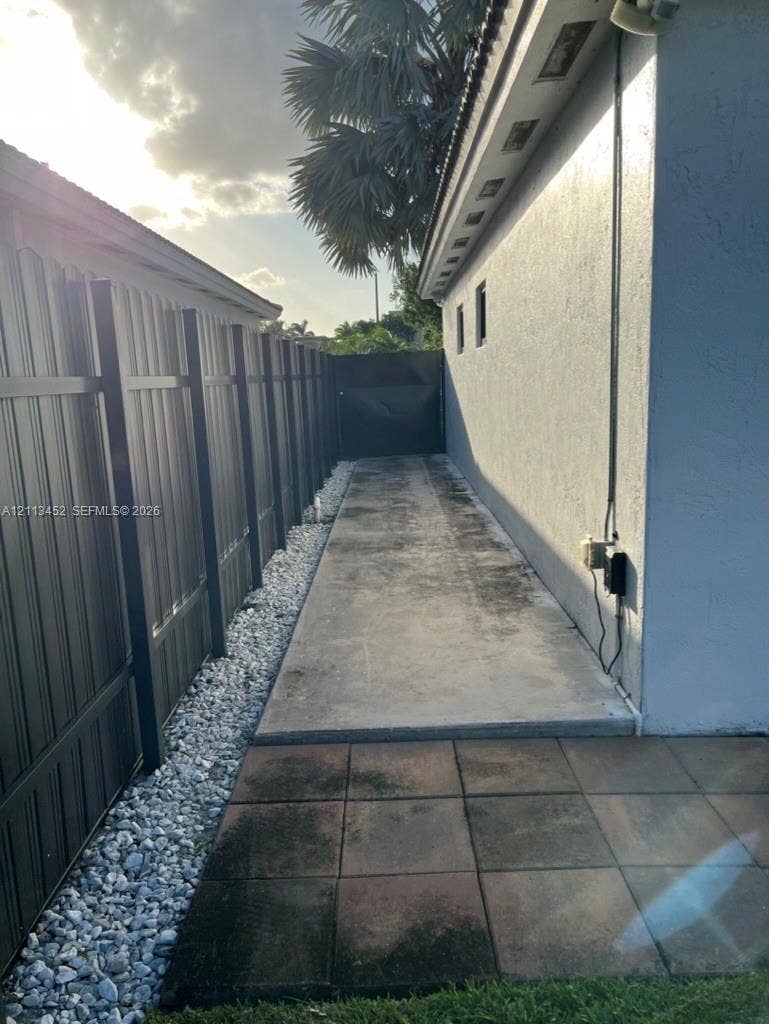 5083 SW 160th Avenue, Miami, Miami, FL 33185 Exterior side path featuring a concrete walkway, decorative stone border, privacy fencing, and paved patio section