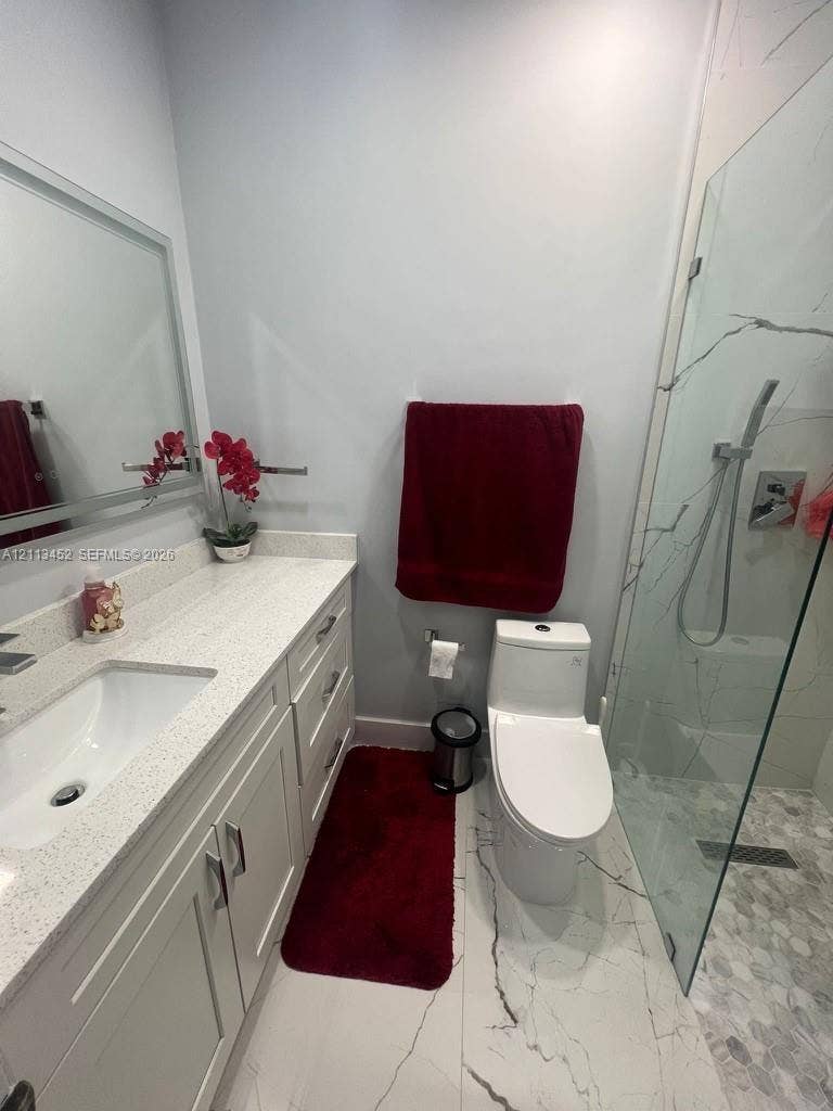 5083 SW 160th Avenue, Miami, Miami, FL 33185 Bathroom featuring a vanity with a light-toned countertop, integrated rectangular sink, framed mirror, and a walk-in shower enclosed by a glass panel with large-format tile flooring