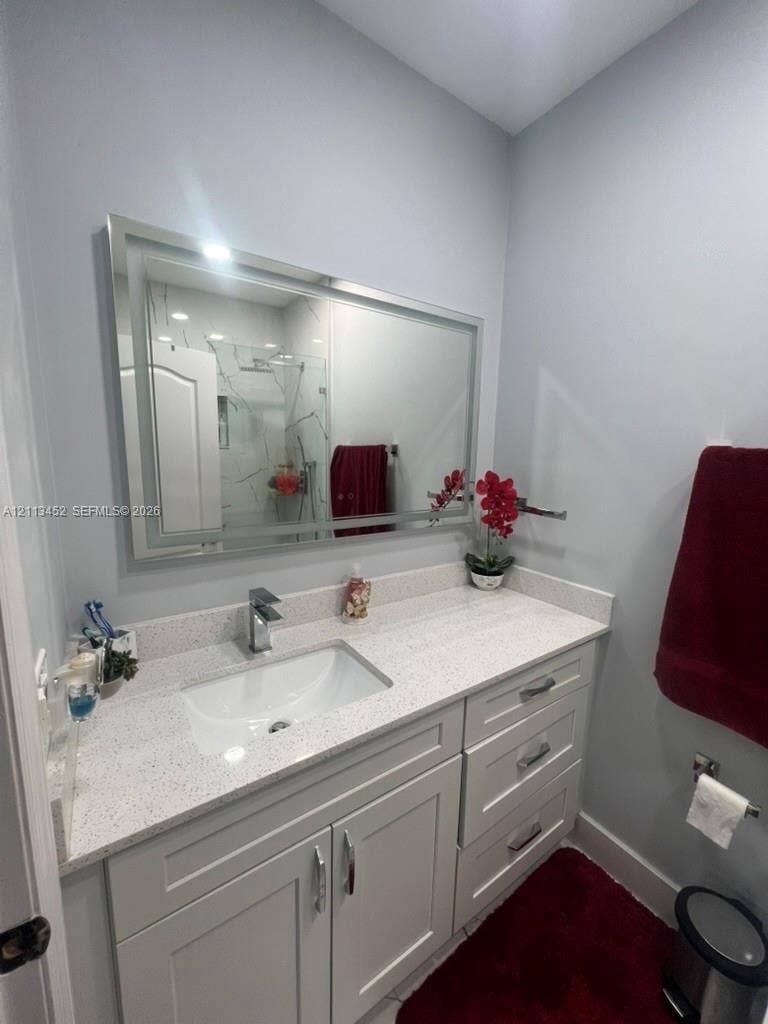 5083 SW 160th Avenue, Miami, Miami, FL 33185 Bathroom vanity featuring light-toned cabinetry, a speckled stone countertop, integrated rectangular undermount sink, chrome faucet, and a large rectangular mirror with an integrated light frame