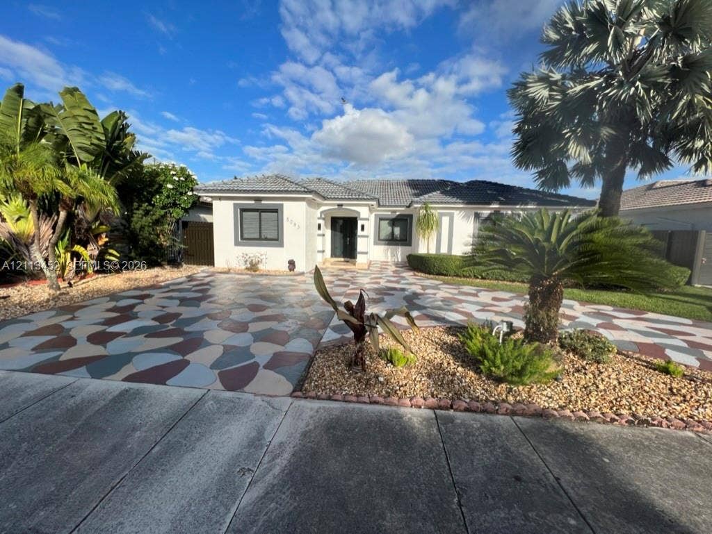 5083 SW 160th Avenue, Miami, Miami, FL 33185 Exterior facade featuring a concrete tile roof, custom-patterned driveway, and manicured landscaping with mature palm trees