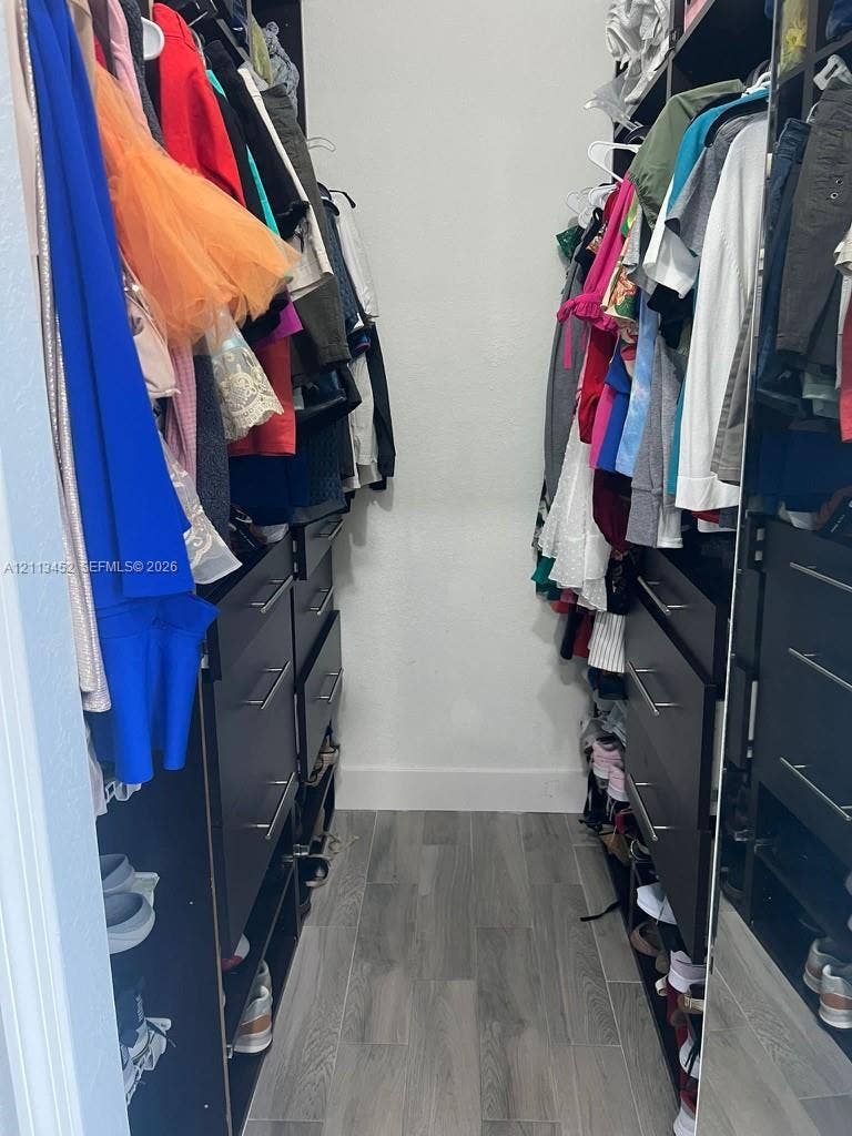 5083 SW 160th Avenue, Miami, Miami, FL 33185 Walk-in closet featuring floor-to-ceiling built-in cabinetry, dark-finish drawers with metallic pulls, open shelving, and wood-finish flooring