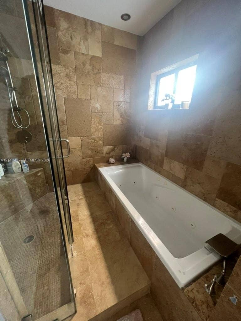 5083 SW 160th Avenue, Miami, Miami, FL 33185 Jetted soaking tub with tile surround, glass-enclosed shower, and natural stone wall and floor tile finishes