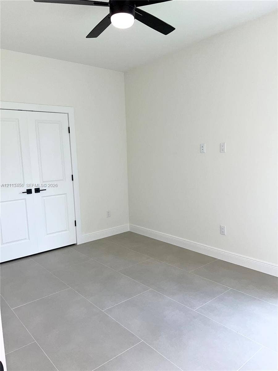 422 SE Eisenhower Boulevard, Lehigh Acres, FL 33974 Neutral-toned tile flooring, double-panel doors with matte black hardware, and a ceiling-mounted light fixture with a fan