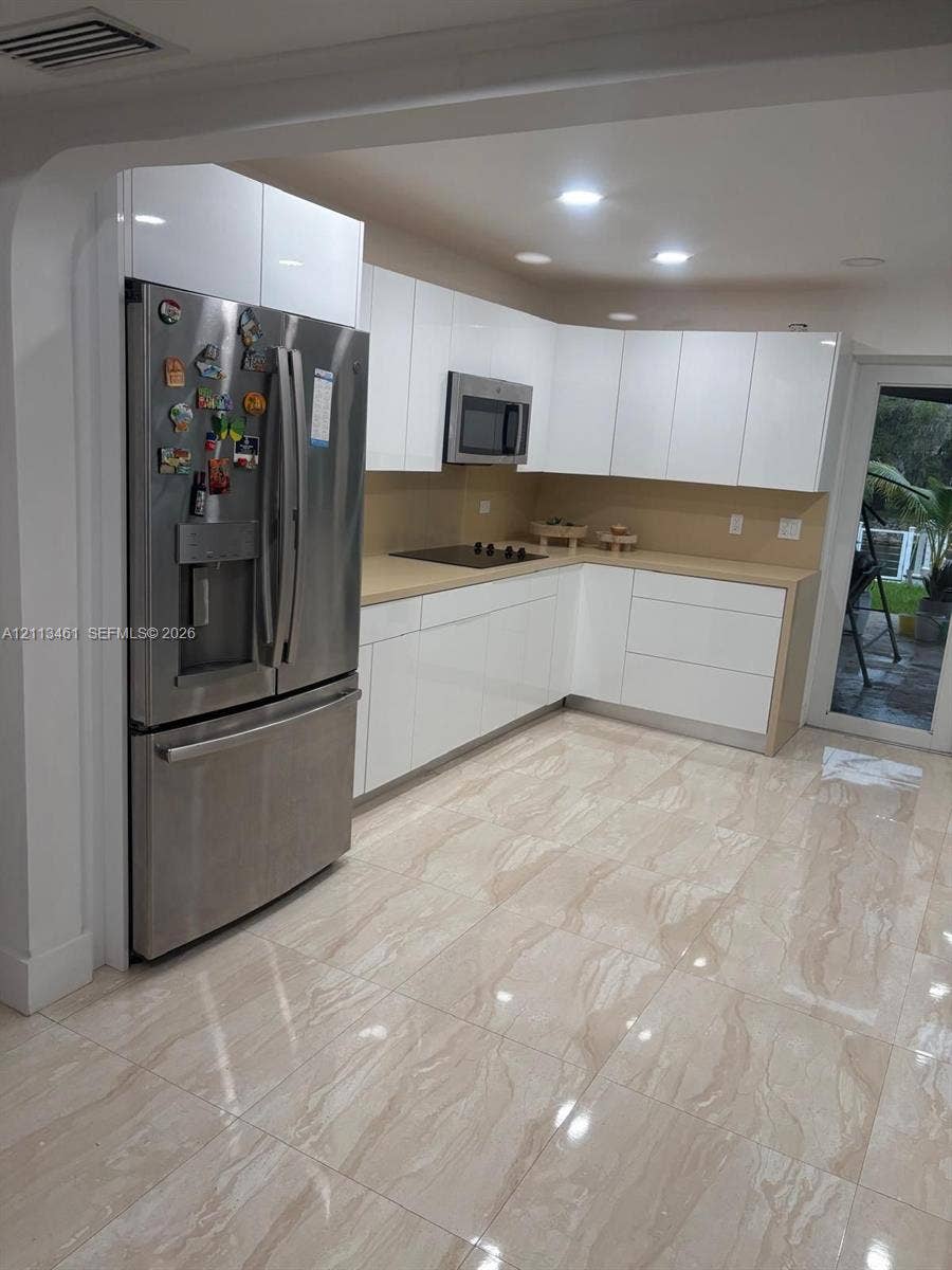 9961 SW 20th Street, Miami, Miami, FL 33165 Kitchen featuring high-gloss white cabinetry, solid-surface countertops, stainless steel refrigerator and built-in microwave, and large-format tile flooring