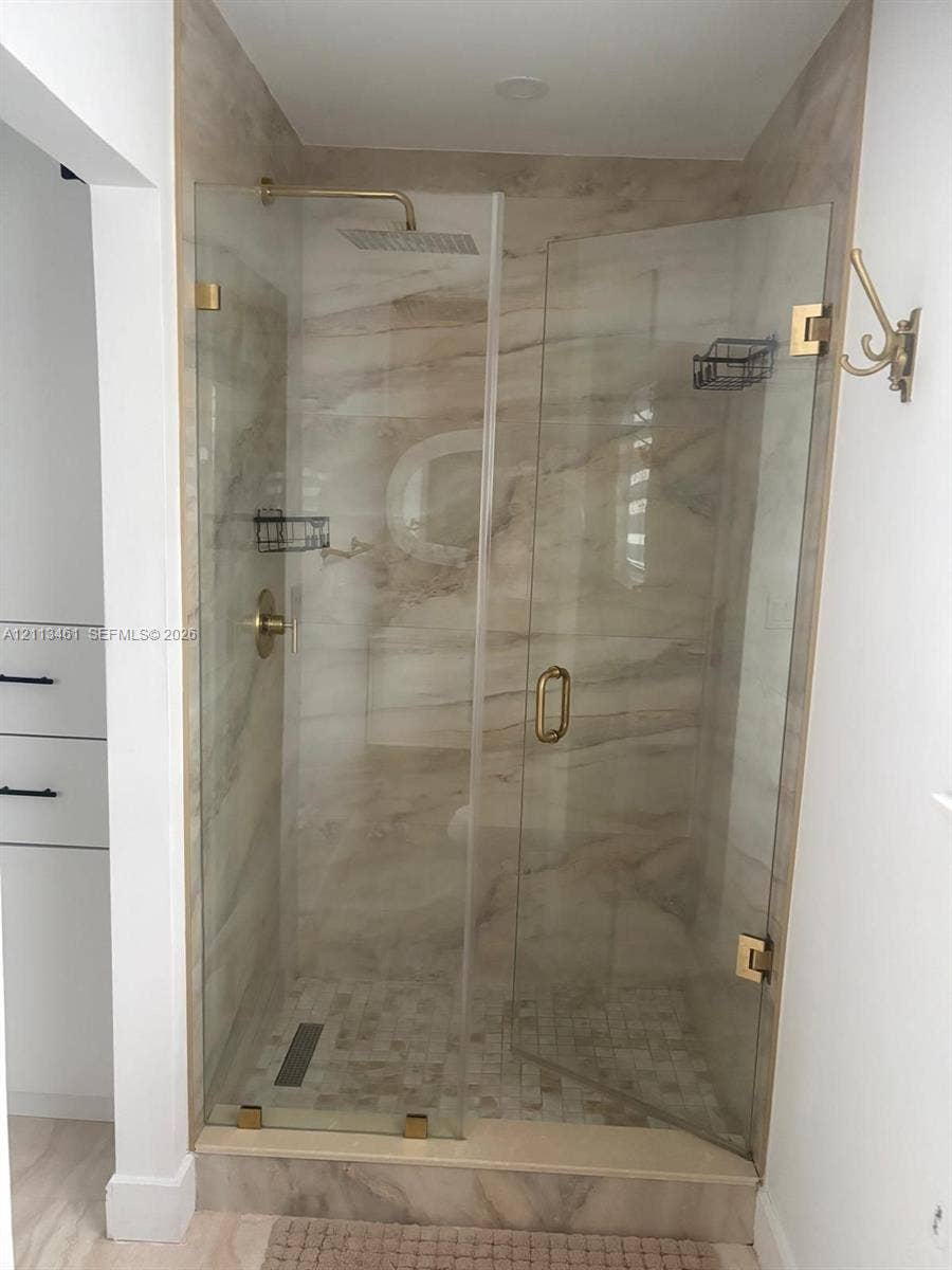 9961 SW 20th Street, Miami, Miami, FL 33165 Walk-in shower featuring large-format stone-pattern wall tile, mosaic stone floor tile, frameless glass enclosure, brass-finish rainfall shower head, and matching brass-finish hardware