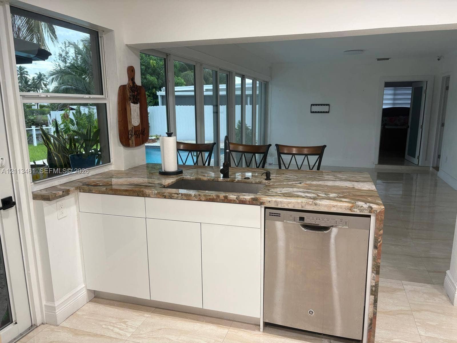 9961 SW 20th Street, Miami, Miami, FL 33165 Kitchen island featuring natural stone waterfall countertops, flat-panel white cabinetry, a stainless steel dishwasher, and an under-mount sink with a matte black faucet