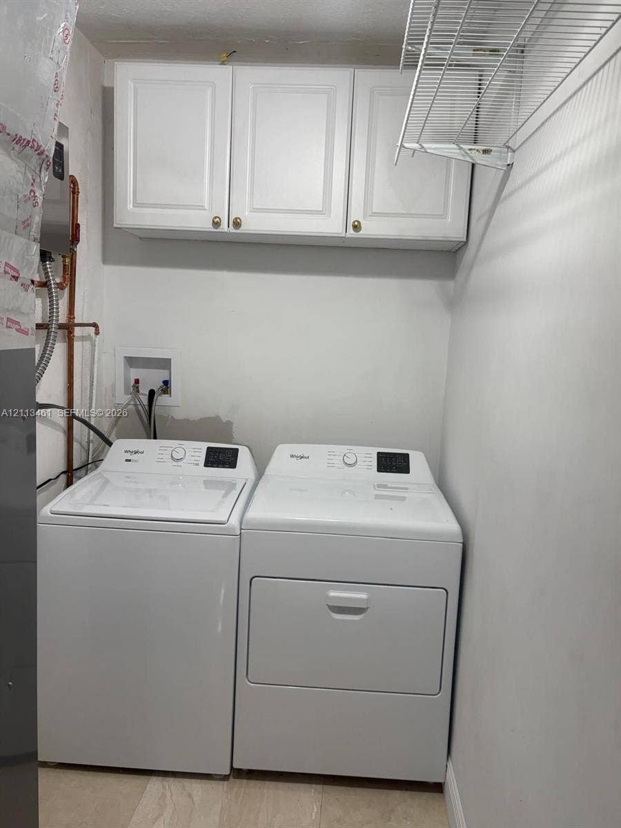9961 SW 20th Street, Miami, Miami, FL 33165 Laundry area featuring white cabinetry, a wall-mounted wire shelving unit, and dedicated washer and dryer hookups