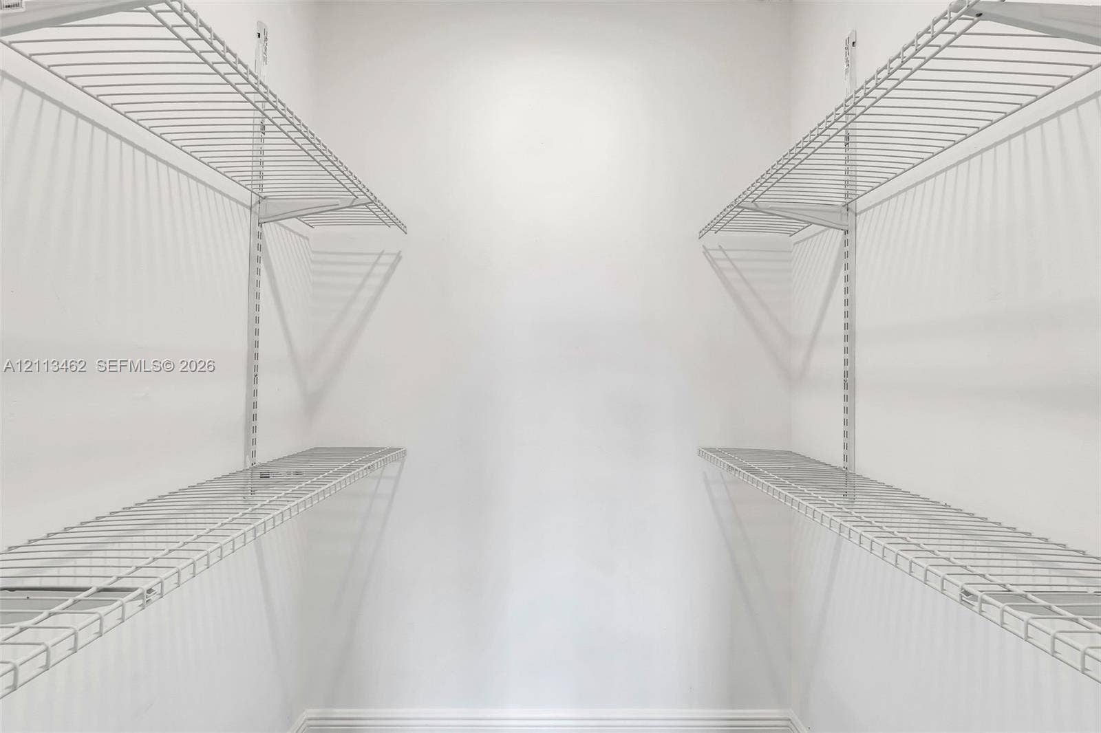 Storage space featuring dual-level white wire shelving units mounted on vertical wall tracks
