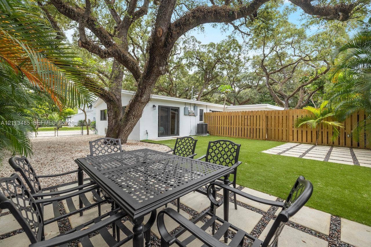 1505 SW 32nd Court, #1, Fort Lauderdale, Fort Lauderdale, FL 33315 Rear yard featuring a paved patio with geometric stone pavers, low-maintenance artificial turf, a wood privacy fence, and mature trees