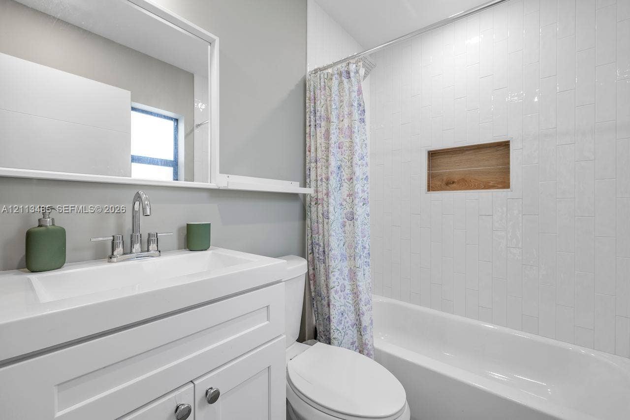 1505 SW 32nd Court, #1, Fort Lauderdale, Fort Lauderdale, FL 33315 Bathroom featuring a white vanity with integrated basin, polished chrome faucet, rectangular wall mirror, white vertical subway tile surround, and built-in wood-finish shower niche