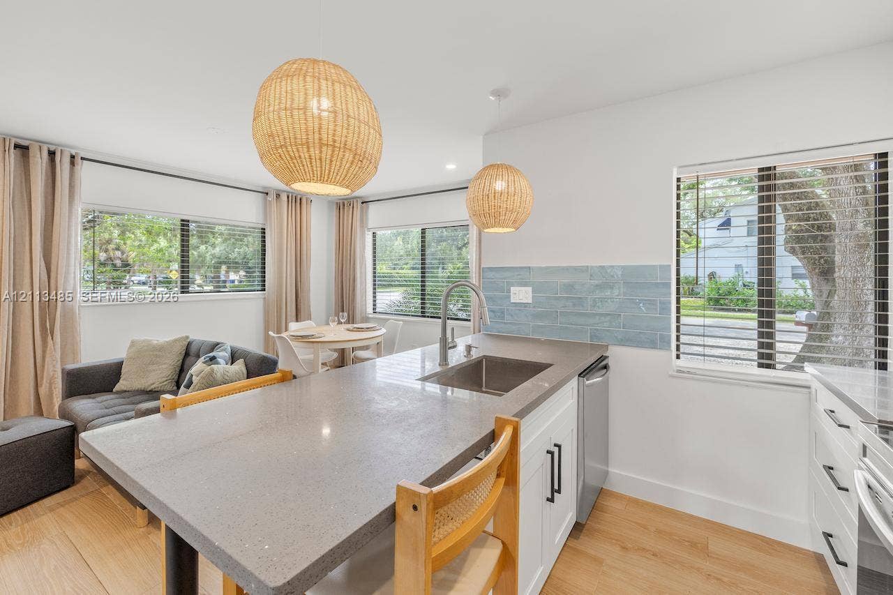 1505 SW 32nd Court, #1, Fort Lauderdale, Fort Lauderdale, FL 33315 Kitchen featuring a gray composite countertop island, stainless steel undermount sink, blue subway tile backsplash, white cabinetry with matte black hardware, and woven pendant light fixtures