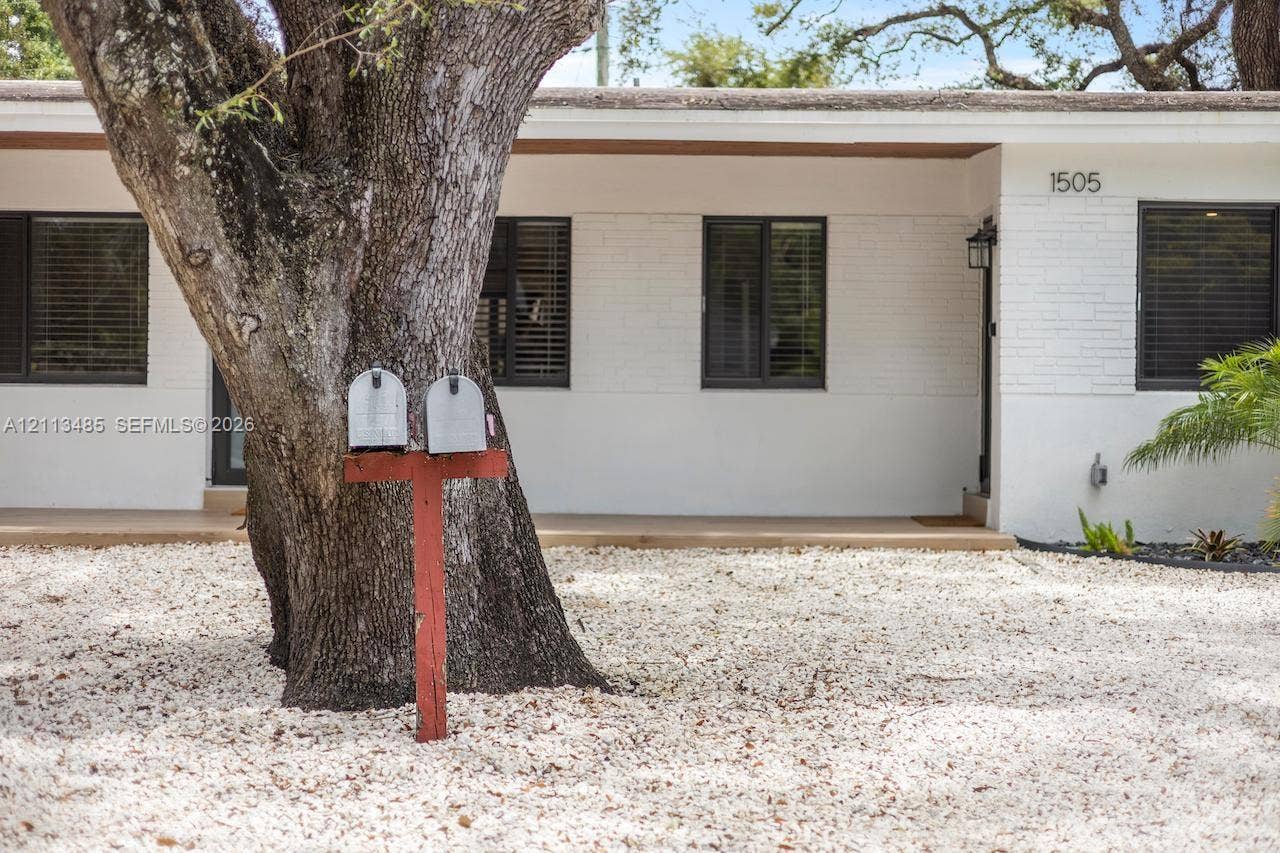 1505 SW 32nd Court, #1, Fort Lauderdale, Fort Lauderdale, FL 33315 Exterior facade featuring painted brick, a covered front porch, dark-framed windows, and xeriscaped front grounds with a mature tree