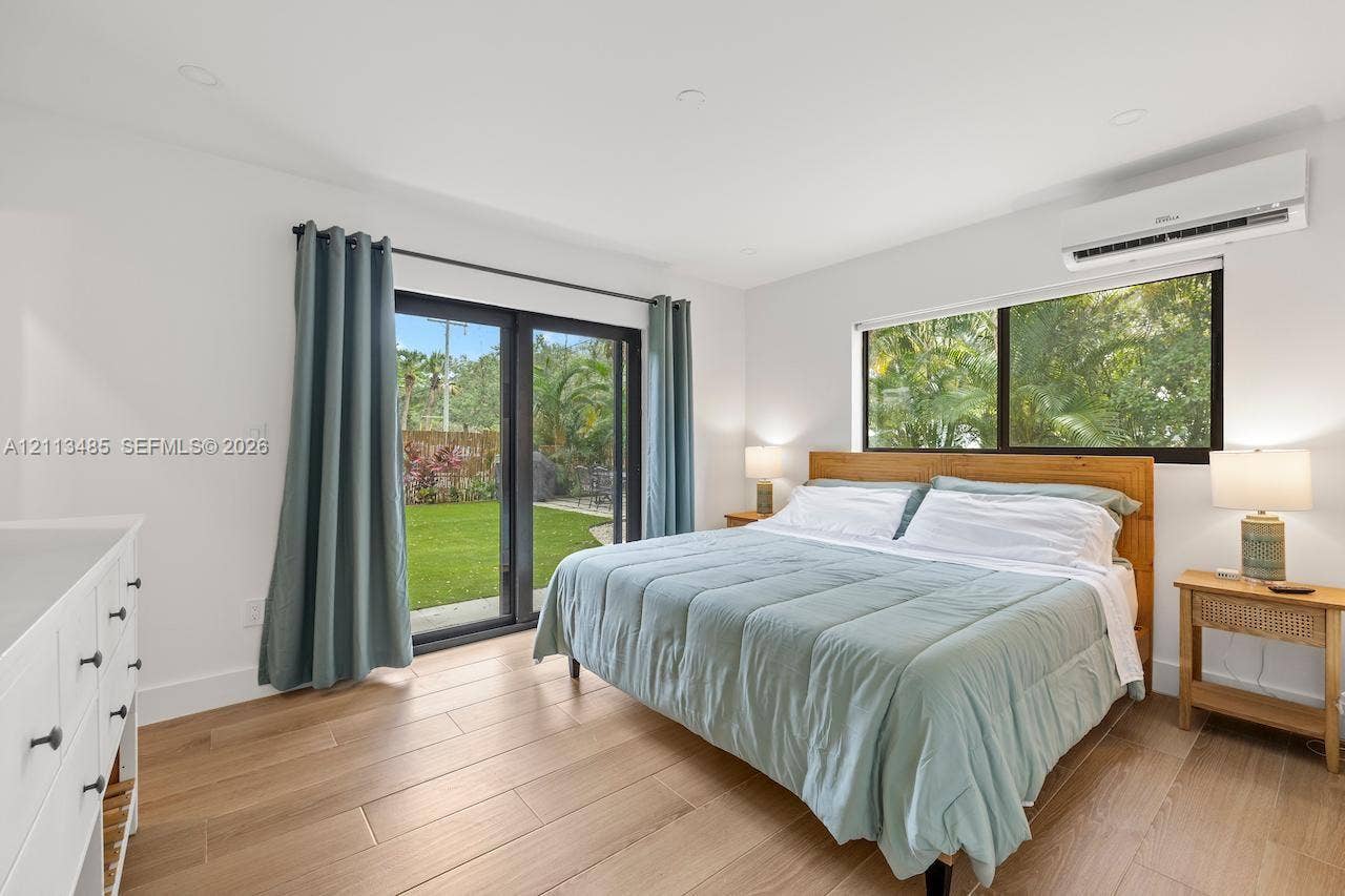 1505 SW 32nd Court, #1, Fort Lauderdale, Fort Lauderdale, FL 33315 Light-filled room featuring wood-finish flooring, recessed lighting, a wall-mounted ductless air conditioning unit, and sliding glass doors with dark frames