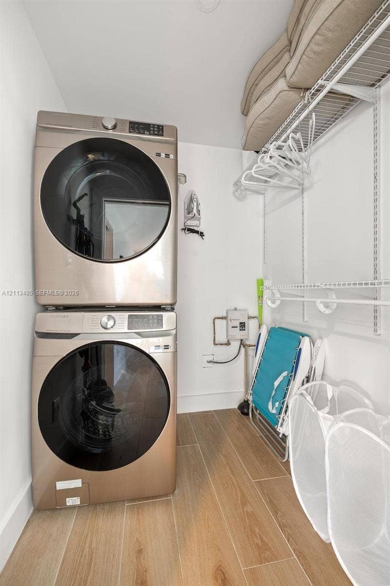 1505 SW 32nd Court, #1, Fort Lauderdale, Fort Lauderdale, FL 33315 Laundry area featuring stacked appliances, wood-finish tile flooring, and integrated wire shelving