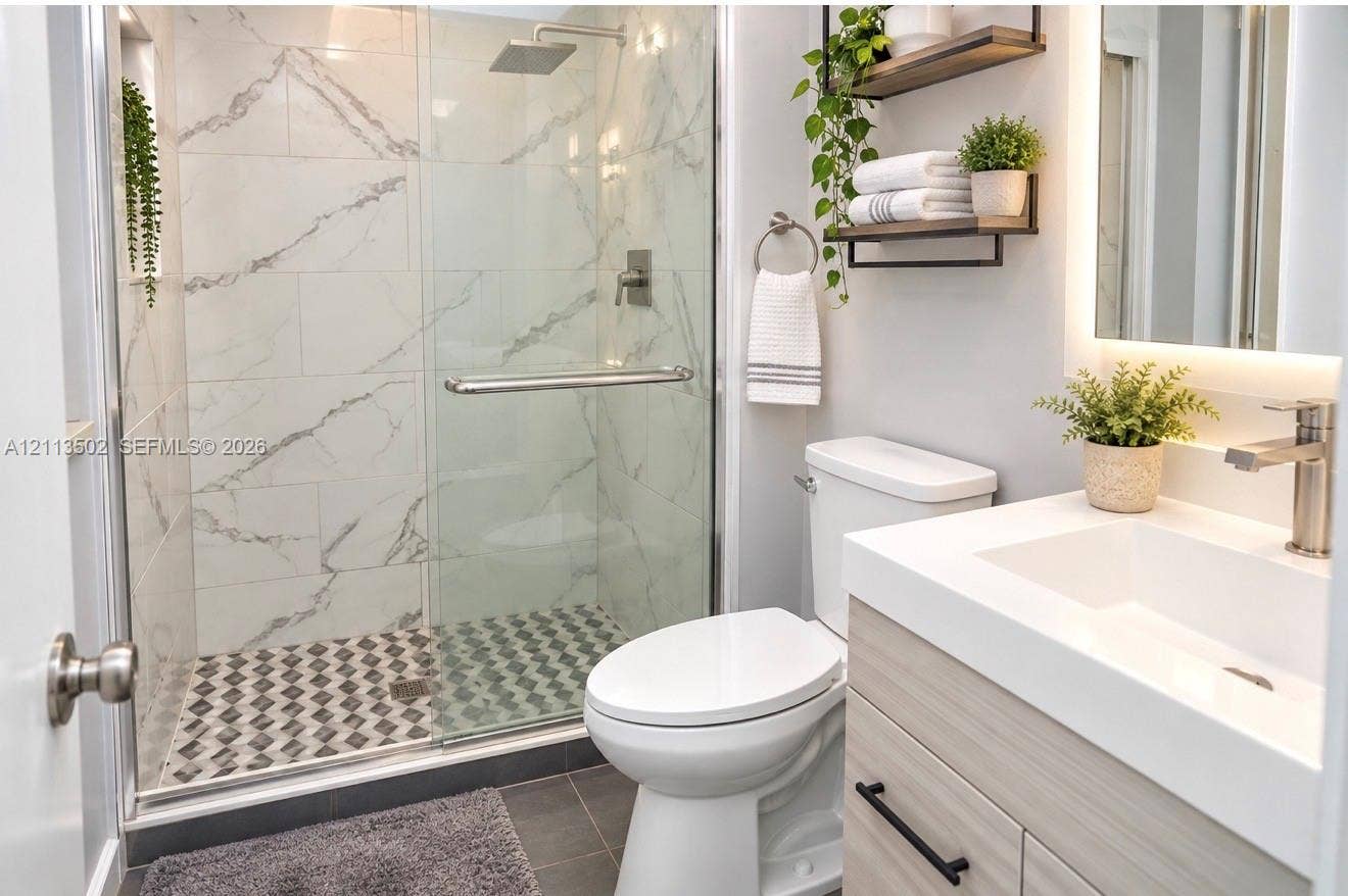 4332 NW 3 Terrace, Deerfield Beach, Deerfield Beach, FL 33064 Walk-in shower with stone-finish tile surround and rain-style showerhead, glass enclosure, vanity with integrated basin and matte black hardware, and wall-mounted shelving