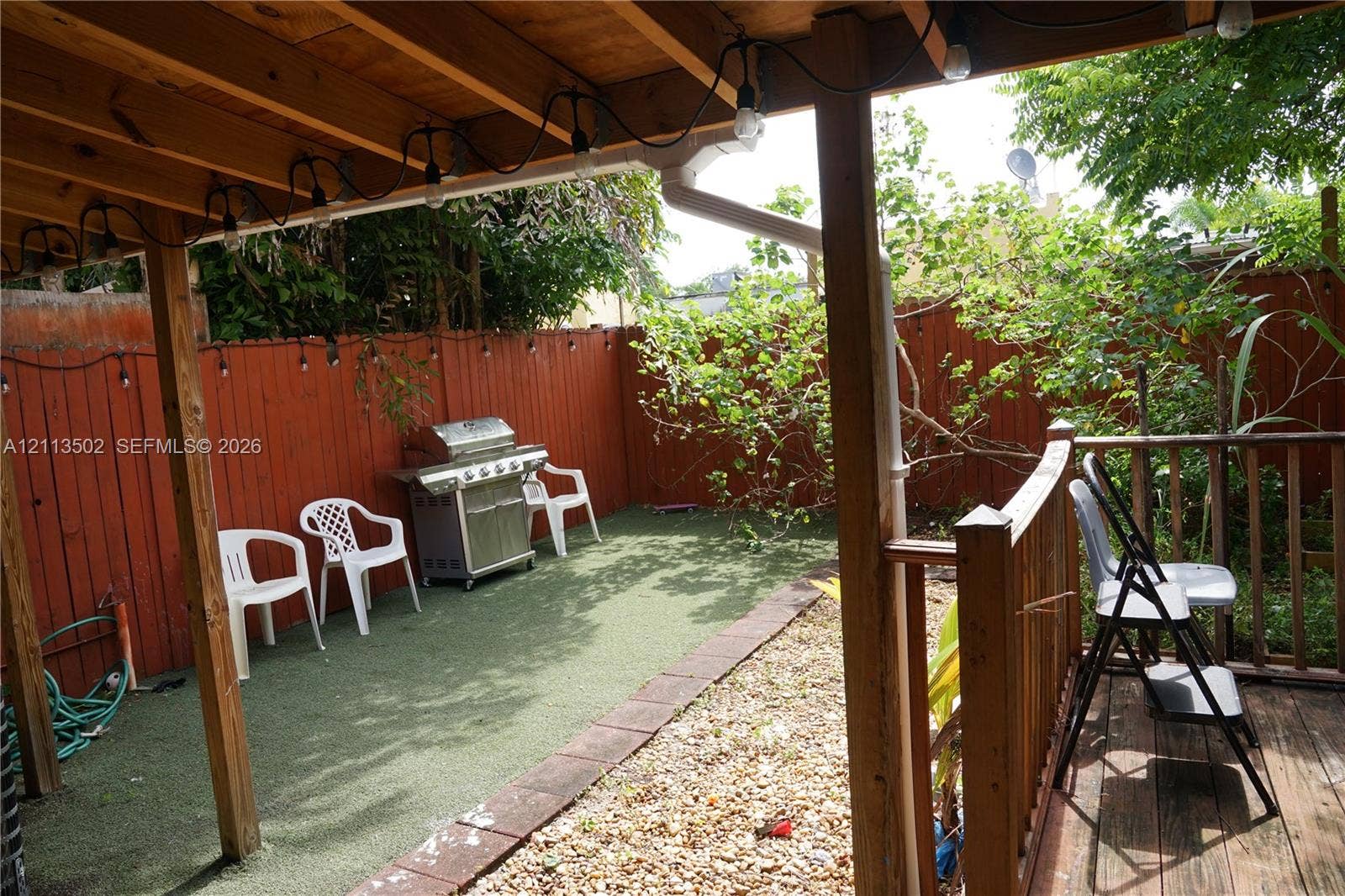 4332 NW 3 Terrace, Deerfield Beach, Deerfield Beach, FL 33064 Covered patio with wood framing, synthetic turf ground cover, perimeter wood fencing, and natural gravel ground cover