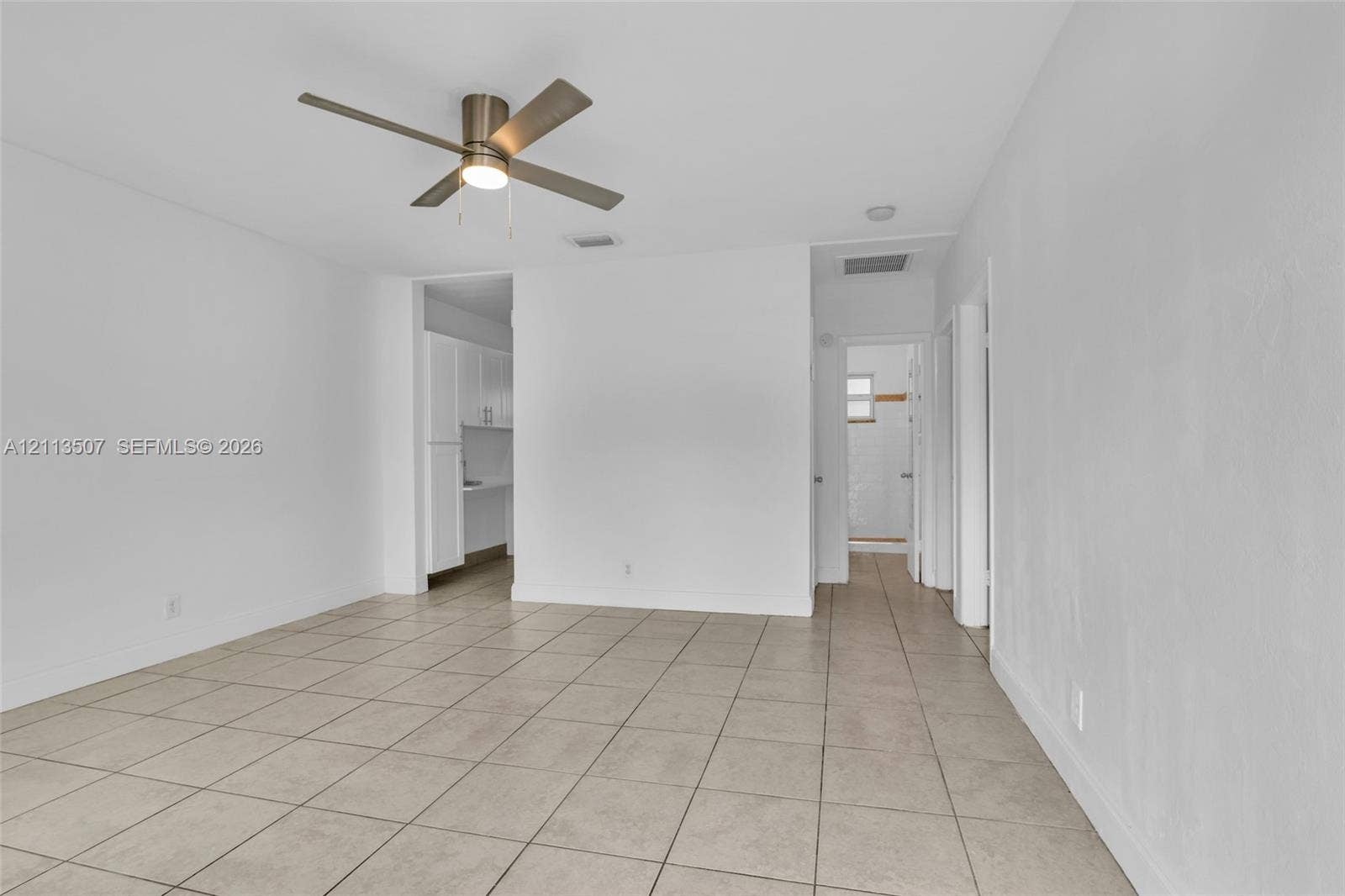 Neutral interior featuring tile flooring, smooth wall finishes, and a ceiling-mounted light fixture with a fan