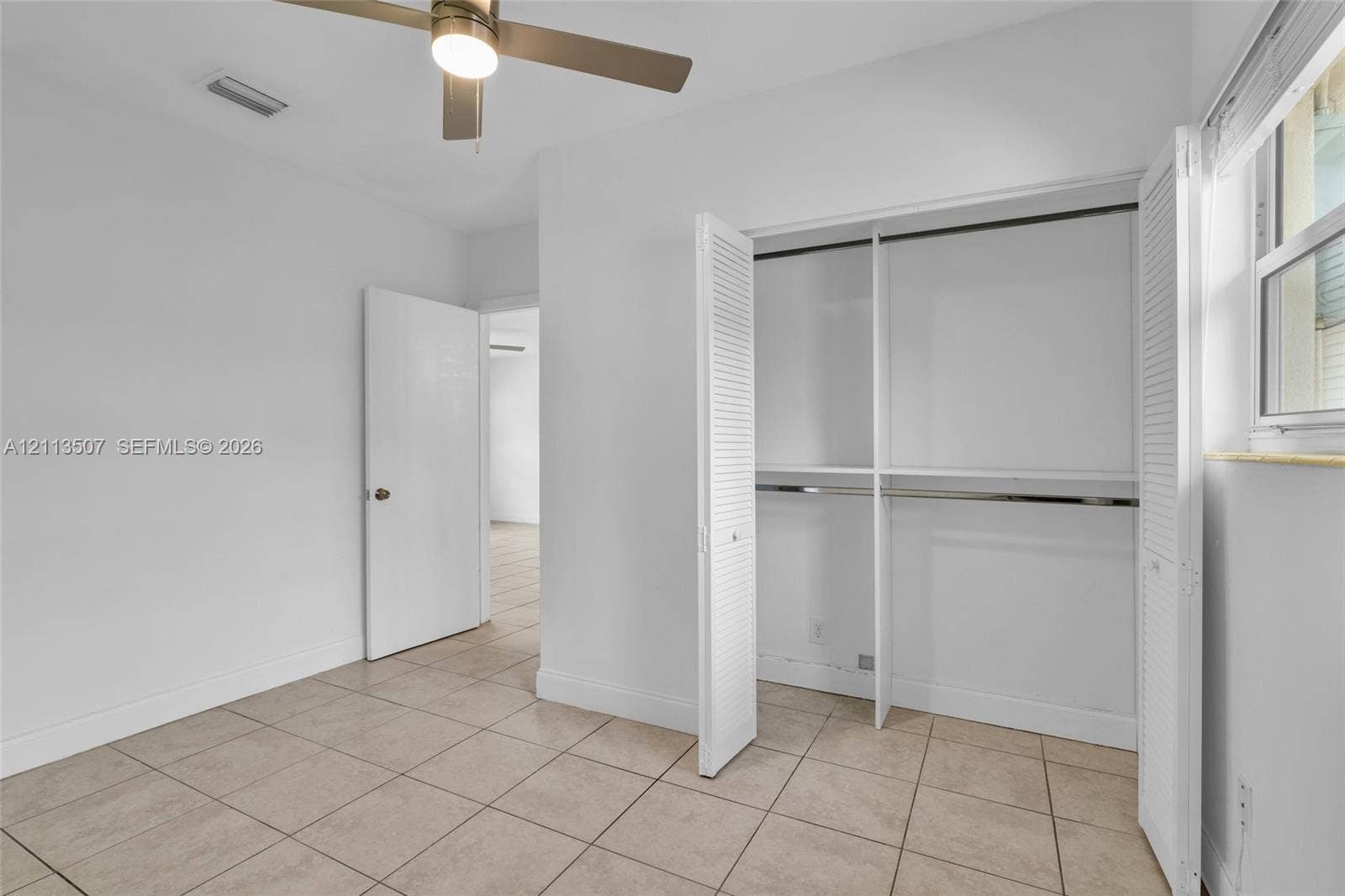 Neutral-toned ceramic tile flooring, closet with bi-fold louvered doors, ceiling fan with integrated lighting, and window with horizontal blinds