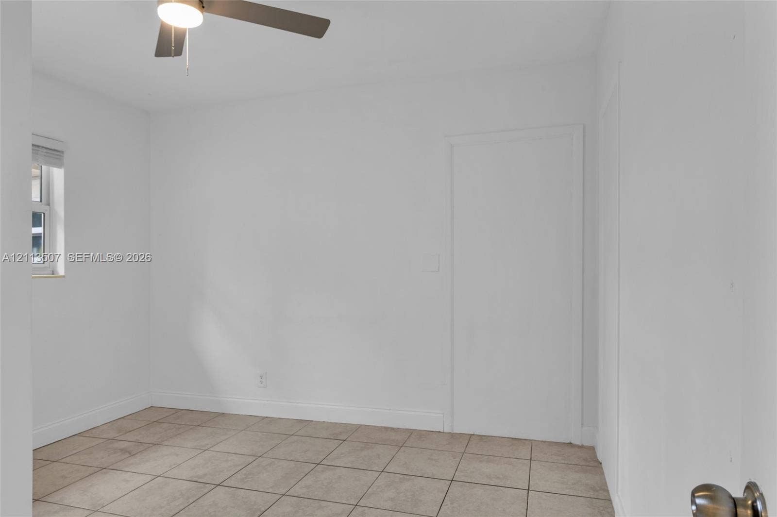 Neutral-toned interior featuring ceramic tile flooring, a window with horizontal blinds, and a ceiling fan with integrated lighting