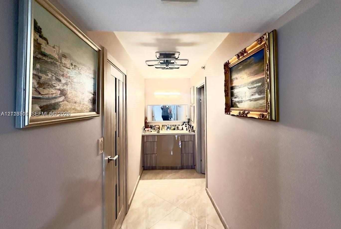1201 S Ocean Drive, #2202S, Hollywood, FL 33019 Hallway featuring neutral-toned walls, tile flooring, a geometric flush-mount light fixture, and a built-in vanity with a stone countertop and rectangular mirror