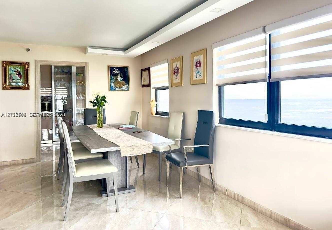 1201 S Ocean Drive, #2202S, Hollywood, FL 33019 Large format tile flooring, tray ceiling with recessed lighting, built-in display cabinetry, and oversized windows with layered roller shades