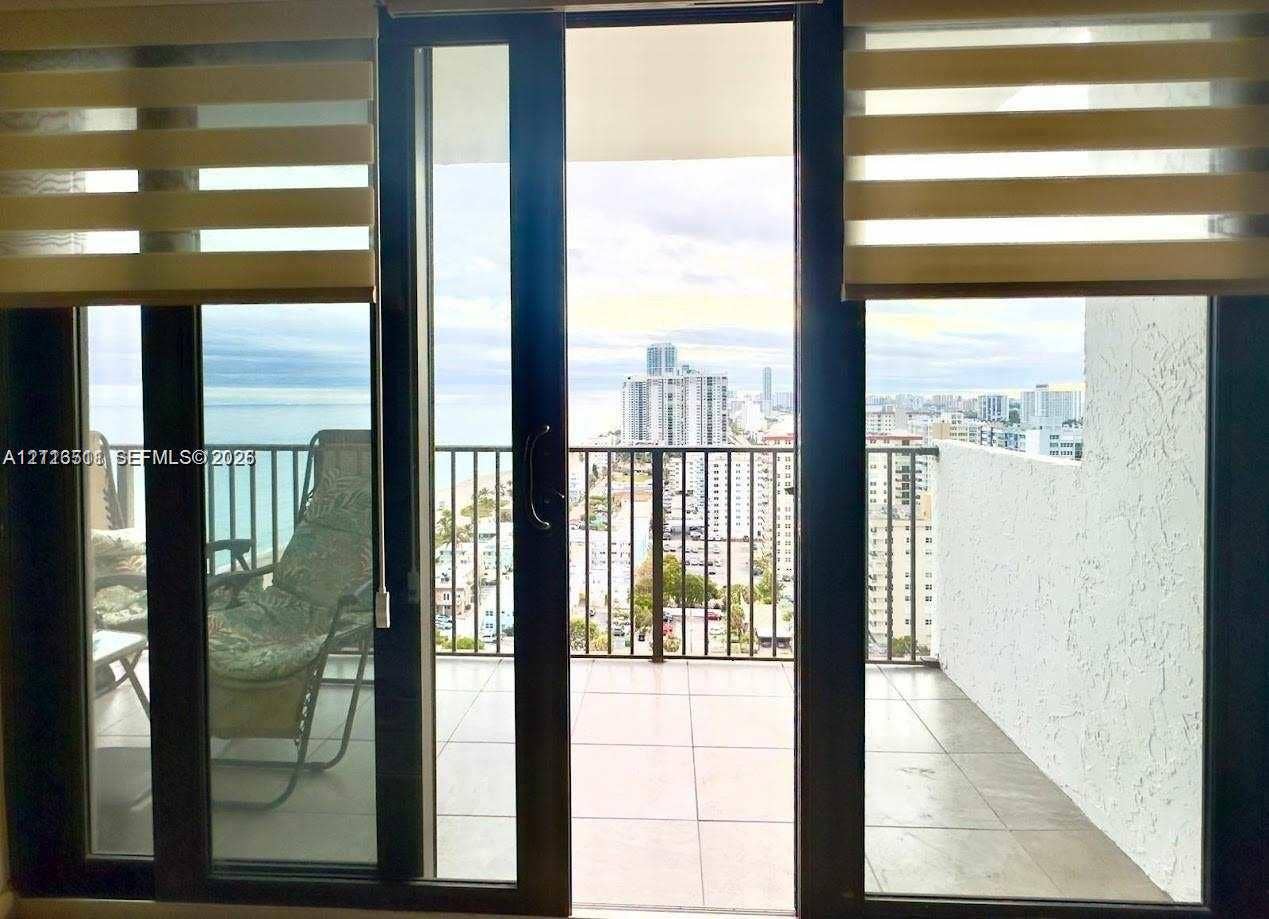 1201 S Ocean Drive, #2202S, Hollywood, FL 33019 Floor-to-ceiling glass sliding doors opening to a private balcony with tile flooring, metal railings, and panoramic coastal and urban scenery