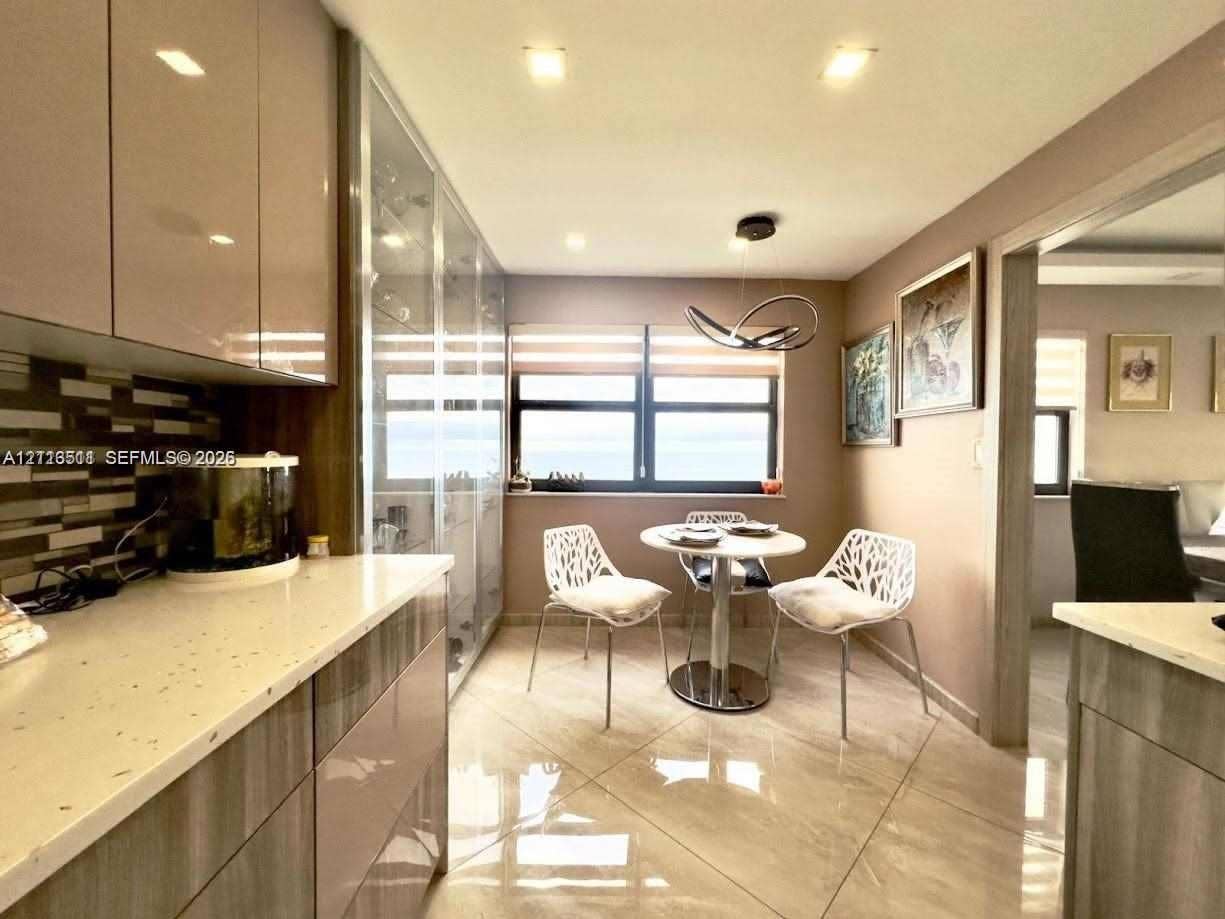 1201 S Ocean Drive, #2202S, Hollywood, FL 33019 High-gloss cabinetry, stone-finish countertops, geometric glass-tile backsplash, floor-to-ceiling built-in display cabinetry, and polished large-format tile flooring