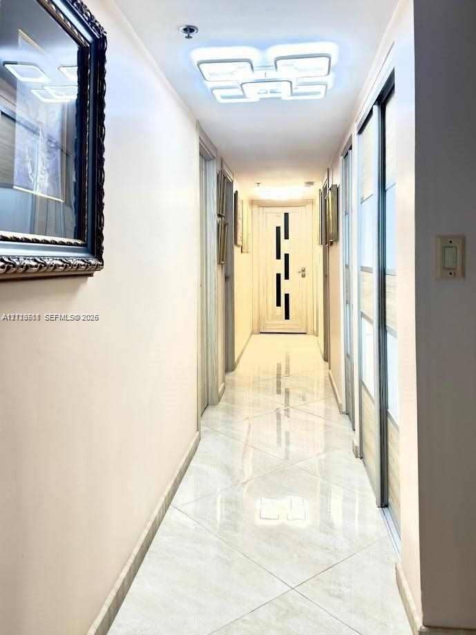 1201 S Ocean Drive, #2202S, Hollywood, FL 33019 Hallway featuring high-gloss tile flooring, geometric LED ceiling light fixture, and sliding door closet with wood-finish paneling