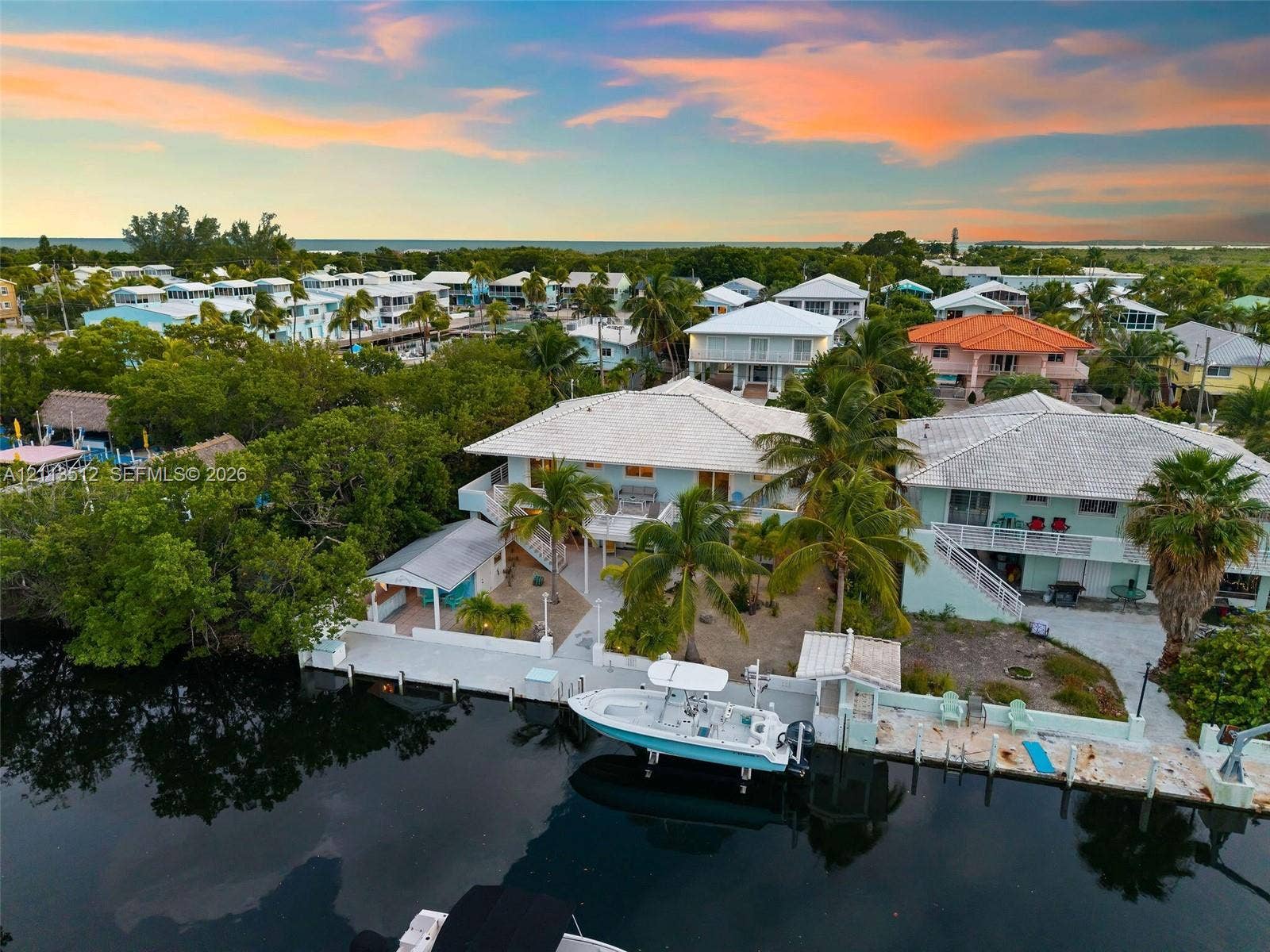 Key Largo, FL 33037 Waterfront residence featuring a private boat dock, concrete seawall, and elevated exterior staircase, situated on a canal with direct water access