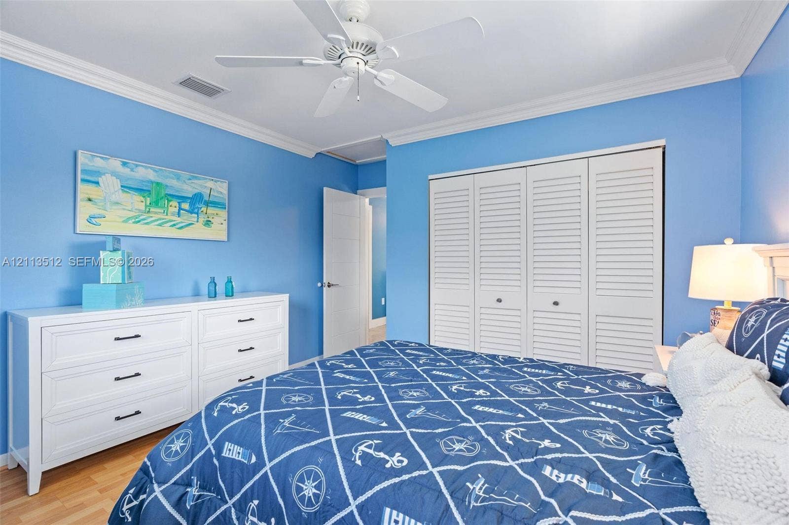 Key Largo, FL 33037 Room featuring wood-finish flooring, white louvered-door closets, crown molding, and a white ceiling fan