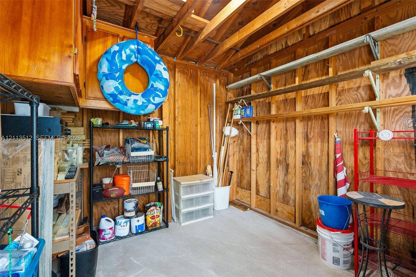 Key Largo, FL 33037 Storage area featuring wood-paneled walls, exposed wood ceiling rafters, wall-mounted shelving, and built-in upper cabinetry