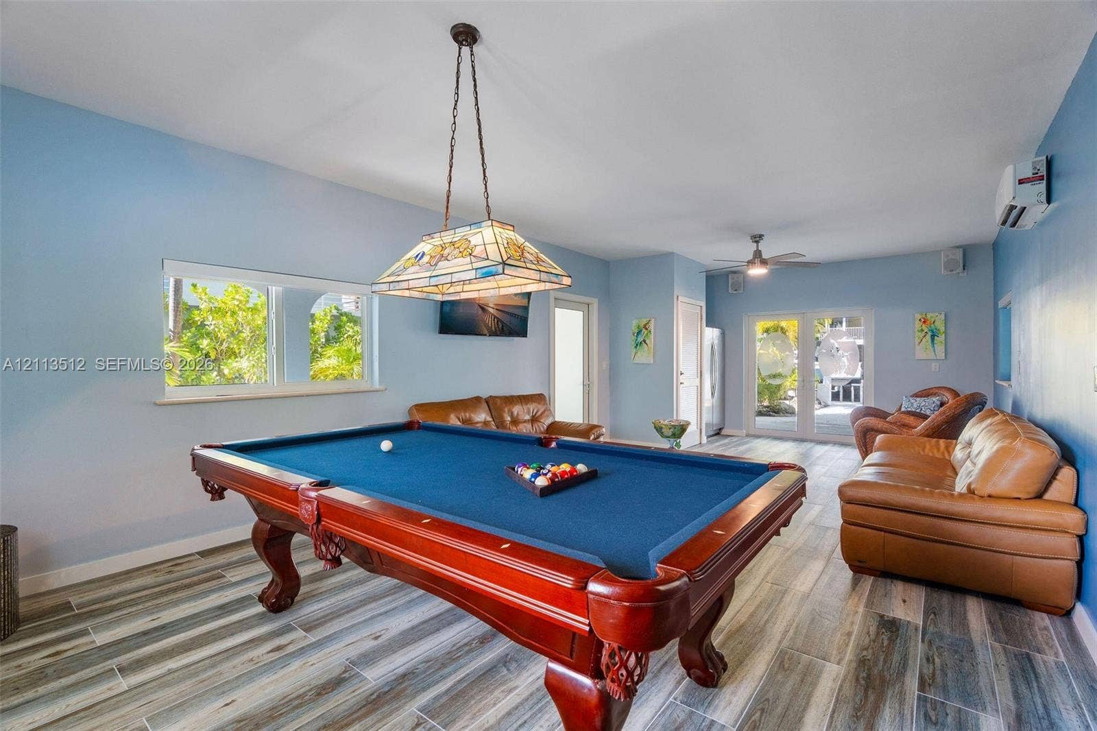 Key Largo, FL 33037 Spacious room featuring wood-finish flooring, stained-glass hanging pendant light, dual-pane windows, and glass-paneled double doors