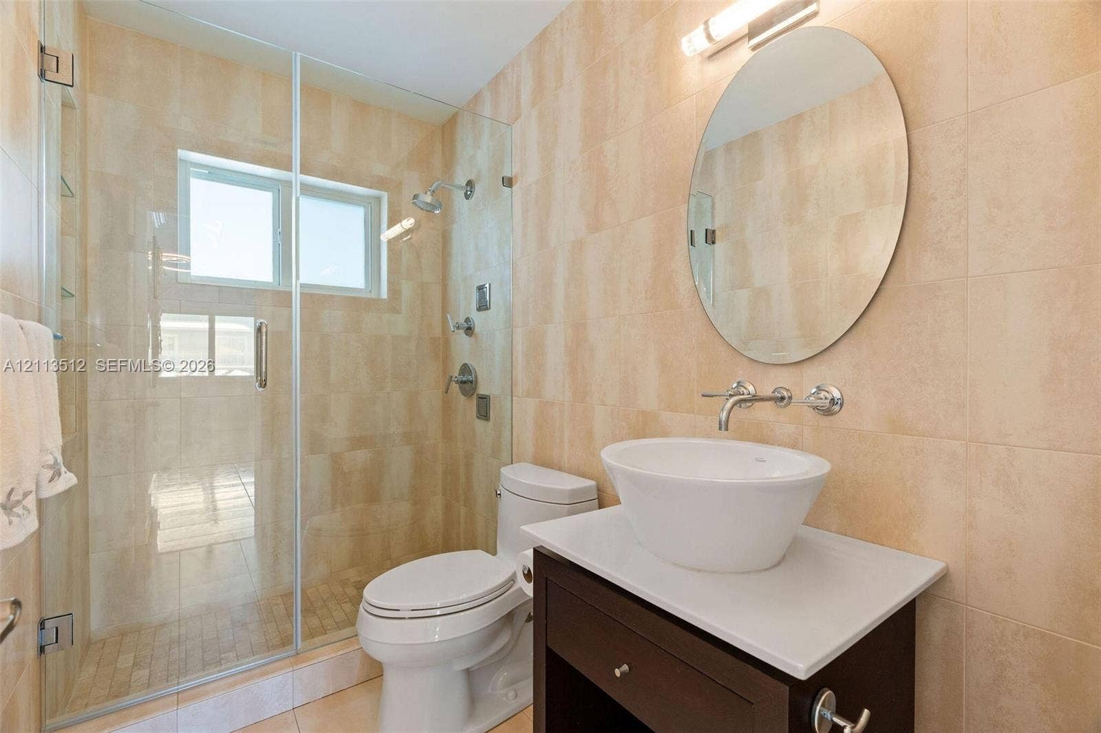 Key Largo, FL 33037 Bathroom featuring a vessel sink with a wall-mounted faucet, vanity with a solid-surface countertop, walk-in shower with a glass enclosure, and wall-to-wall ceramic tile finishes