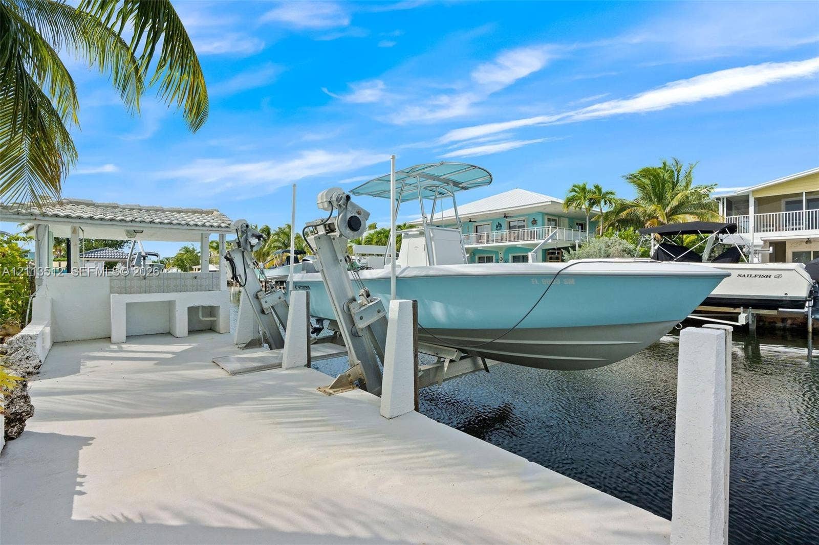 Key Largo, FL 33037 Private dock featuring a boat lift, concrete slip, and a covered cleaning station