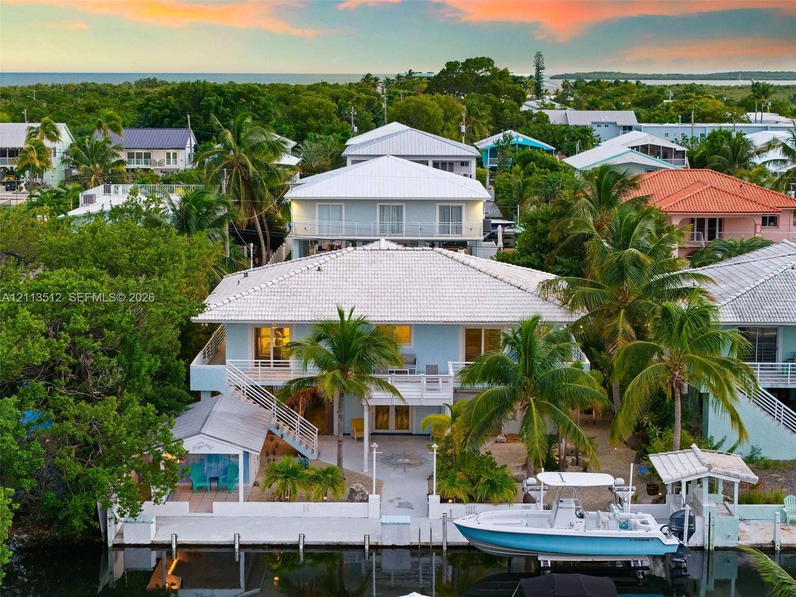 Key Largo, FL 33037 Waterfront property featuring a private concrete dock, multilevel balconies, tile roofing, and mature palm landscaping