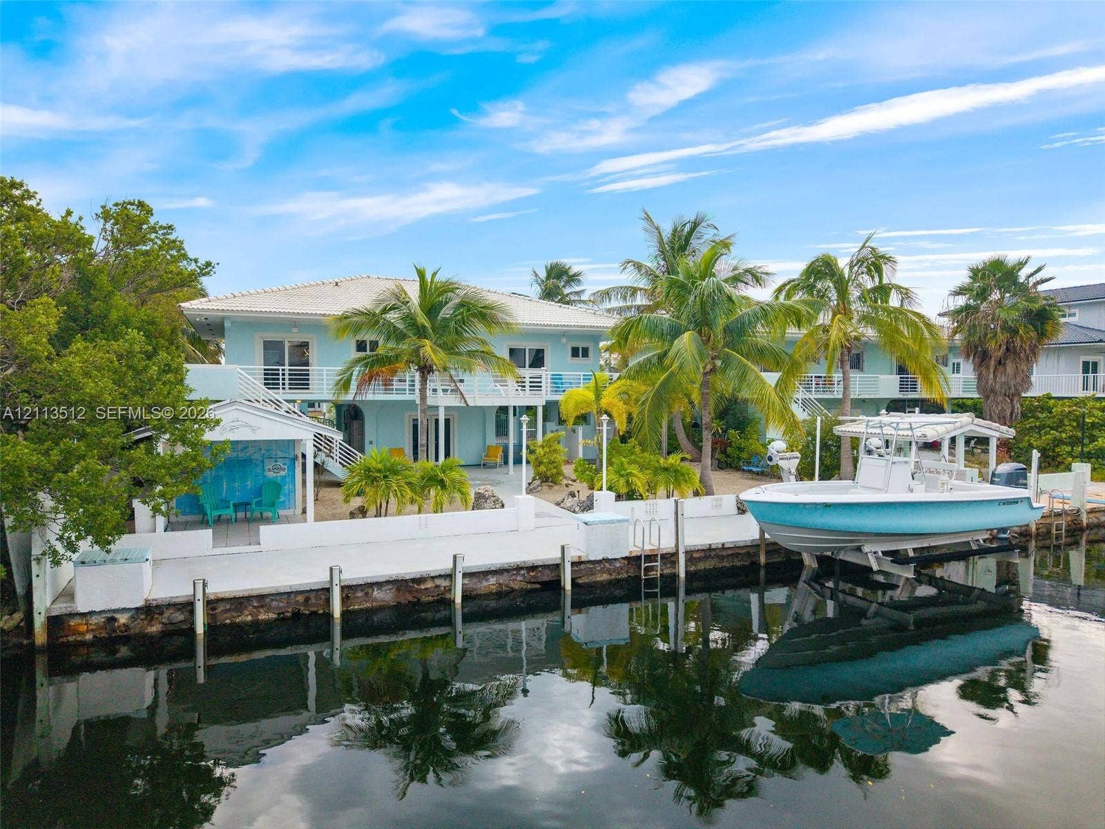 Key Largo, FL 33037 Waterfront property featuring a private boat lift, a concrete bulkhead, paved hardscaping, and an elevated terrace