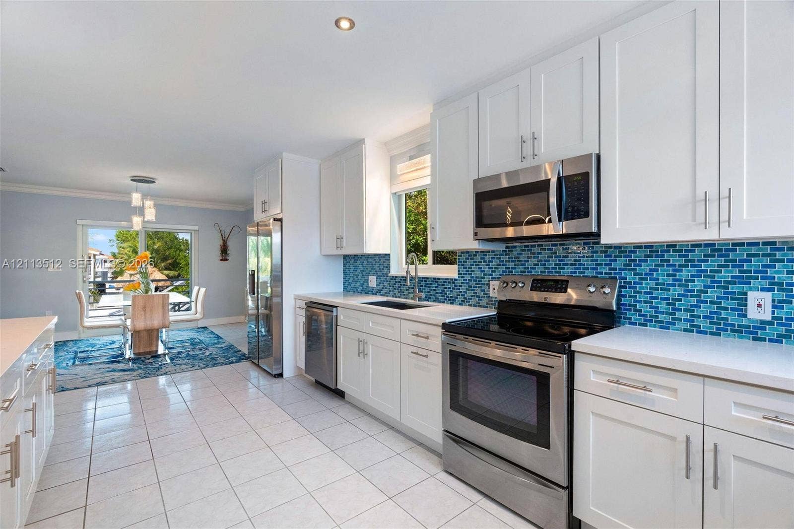 Key Largo, FL 33037 Kitchen featuring white shaker-style cabinetry, stainless steel appliances, blue glass tile backsplash, white countertops, and tile flooring