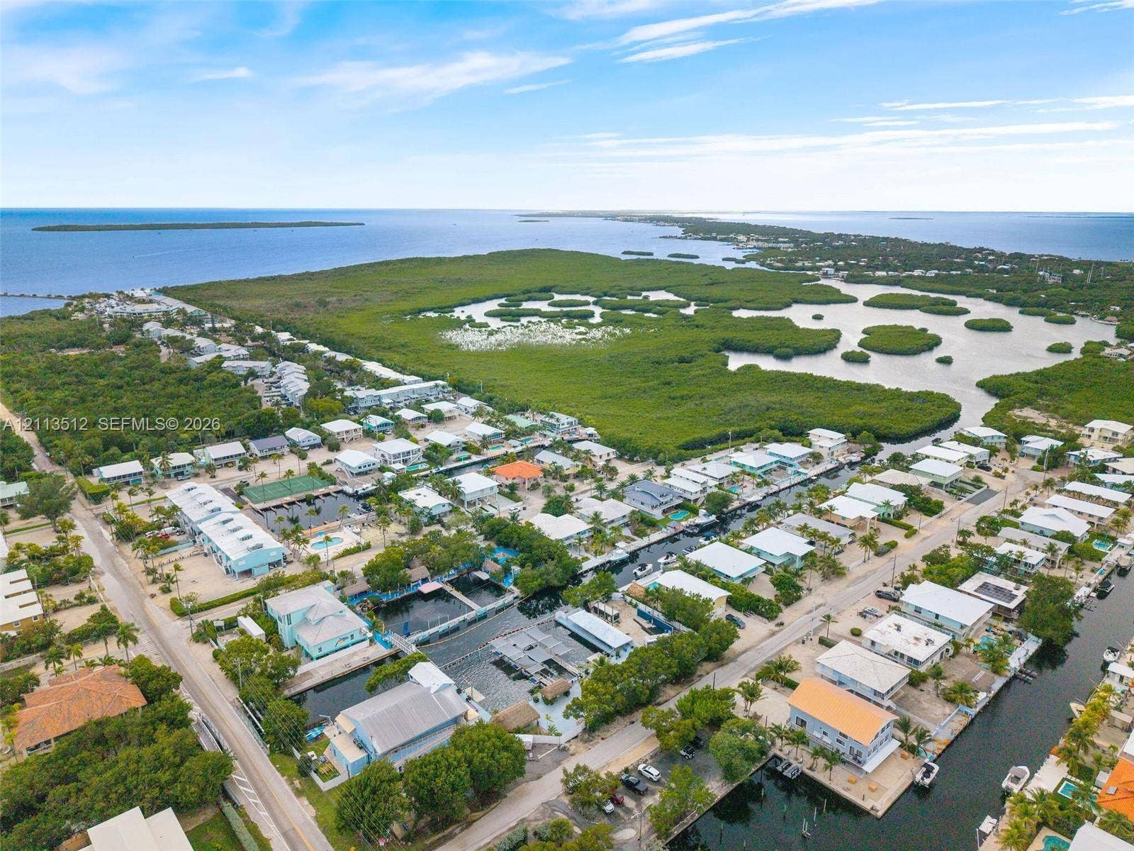 Key Largo, FL 33037 Aerial perspective of a coastal community featuring residential canal-front access, paved street grid, and surrounding natural mangroves